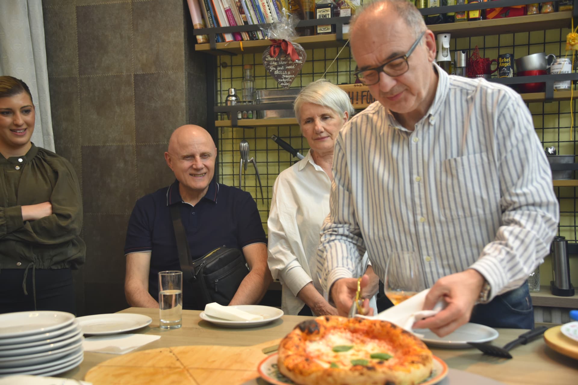 Pizza majstor seče napolitana picu pred nasmejanim polaznicima